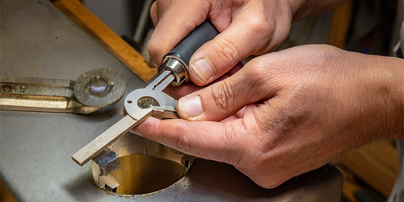 A locksmith deburring a newly cut key.